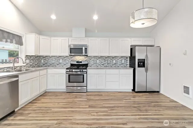 a kitchen with stainless steel appliances a stove top oven a sink and a refrigerator