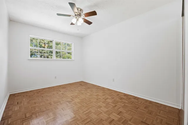 an empty room with a window and a ceiling fan