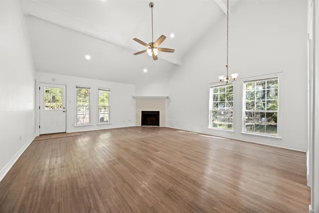 an empty room with wooden floor fan and windows