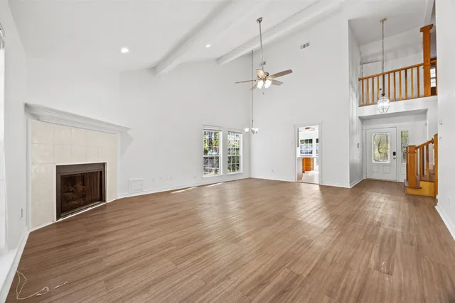 a view of an empty room with wooden floor fireplace and a window
