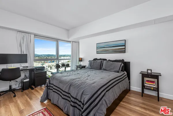 a bedroom with a bed and large windows