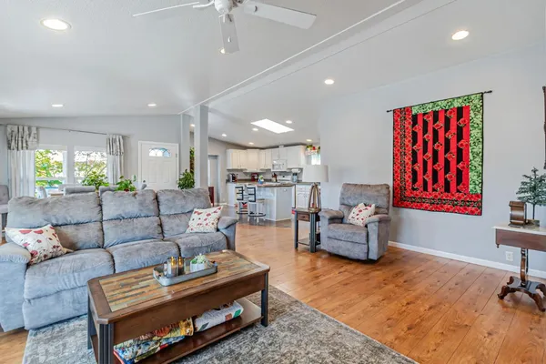 a living room with furniture kitchen view and a wooden floor