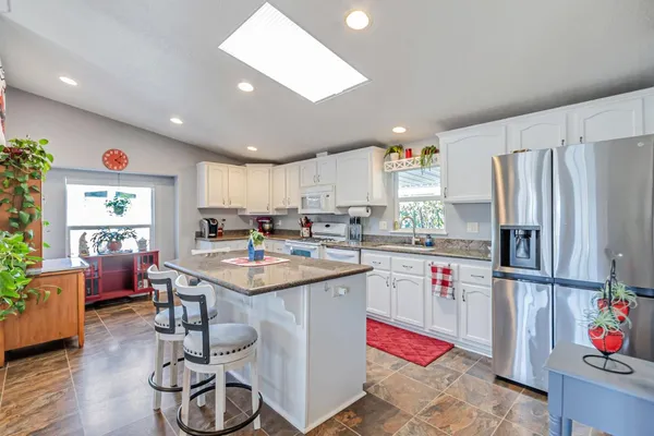 a kitchen with a refrigerator a sink dishwasher and a dining table with wooden floor