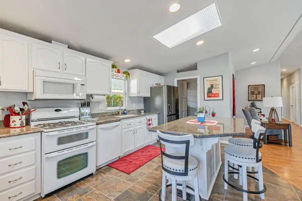 a kitchen with a dining table cabinets appliances and wooden floor
