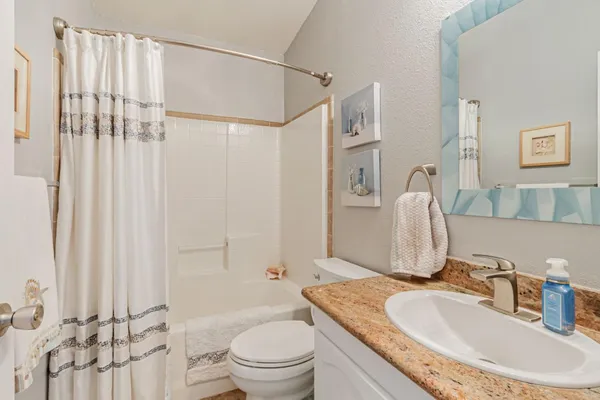 a bathroom with a granite countertop sink toilet a mirror a vanity and shower