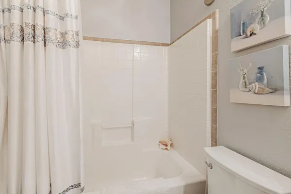 a white bath tub sitting next to a white toilet and curtain