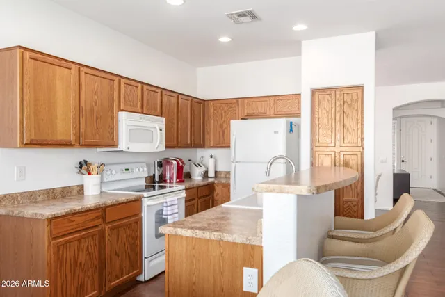a kitchen with stainless steel appliances granite countertop a stove a sink dishwasher and a refrigerator with white cabinets