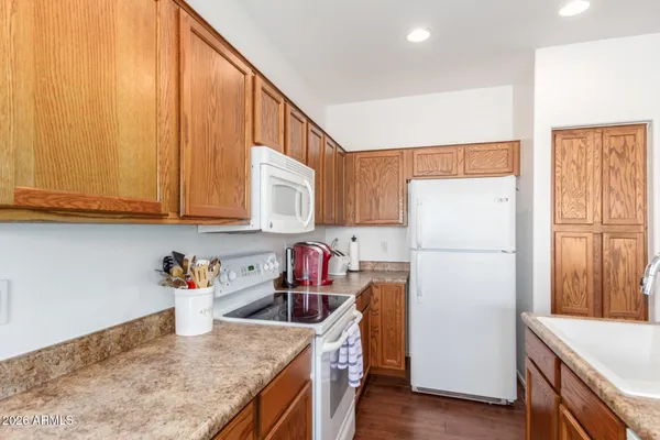 a kitchen with a refrigerator a stove a sink dishwasher and wooden cabinets with wooden floor
