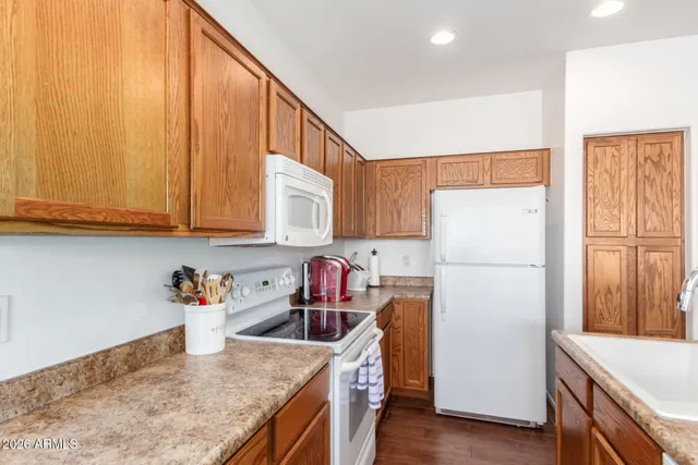 a kitchen with a refrigerator a stove a sink dishwasher and wooden cabinets with wooden floor