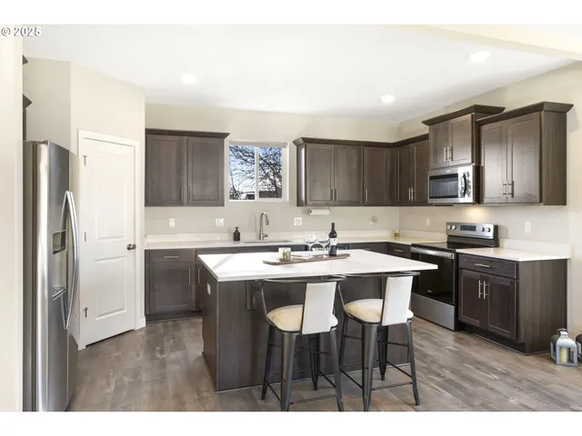 a kitchen with kitchen island granite countertop a sink cabinets and stainless steel appliances