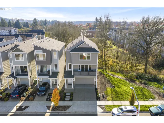 a view of residential houses with cars parked on the roadside