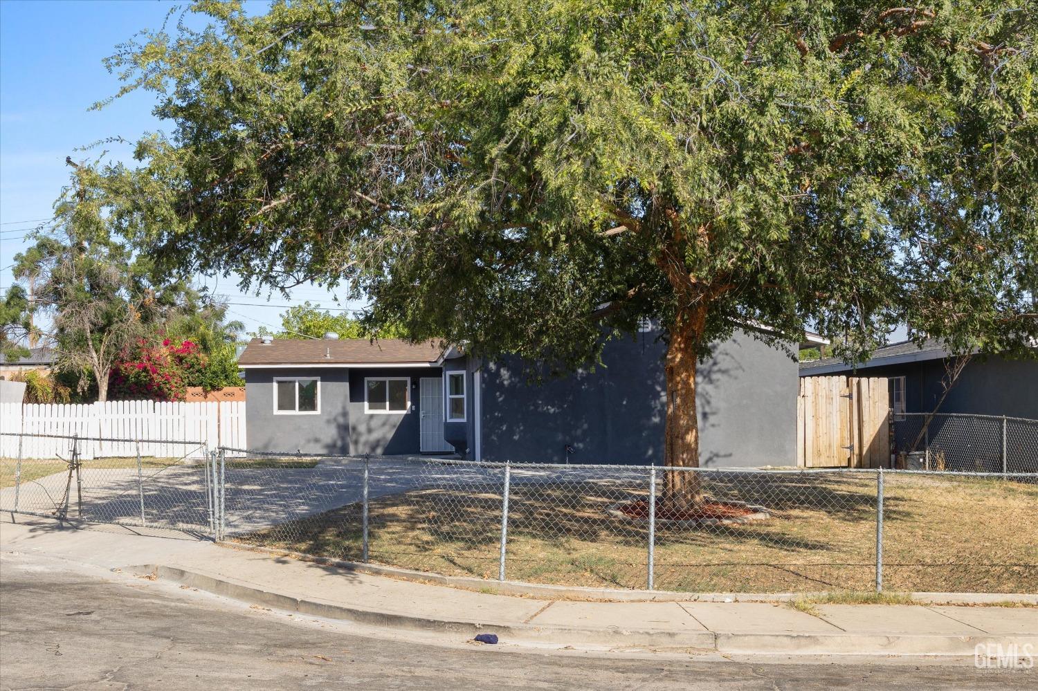 Undisclosed Address Bakersfield, CA 93306 - Photo 3 of 26 a view of a white house with a large tree and yard