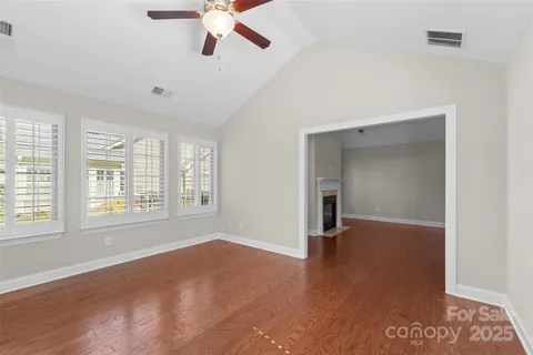 a view of an empty room with a window and wooden floor
