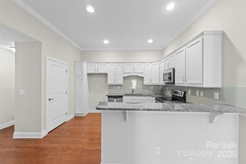 a large kitchen with kitchen island a sink stainless steel appliances and white cabinets