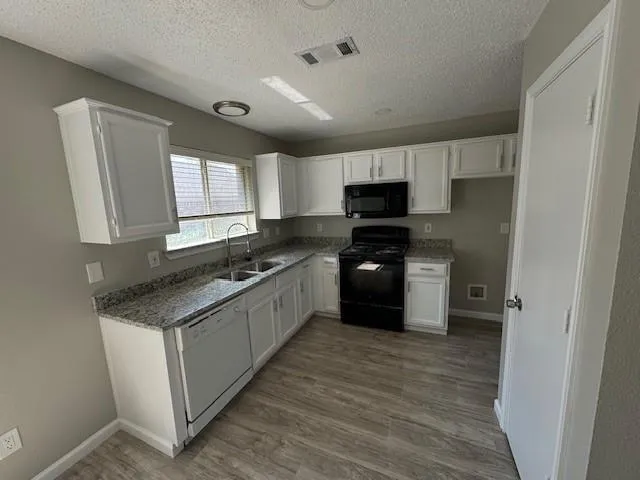 a kitchen with granite countertop a sink cabinets and stainless steel appliances