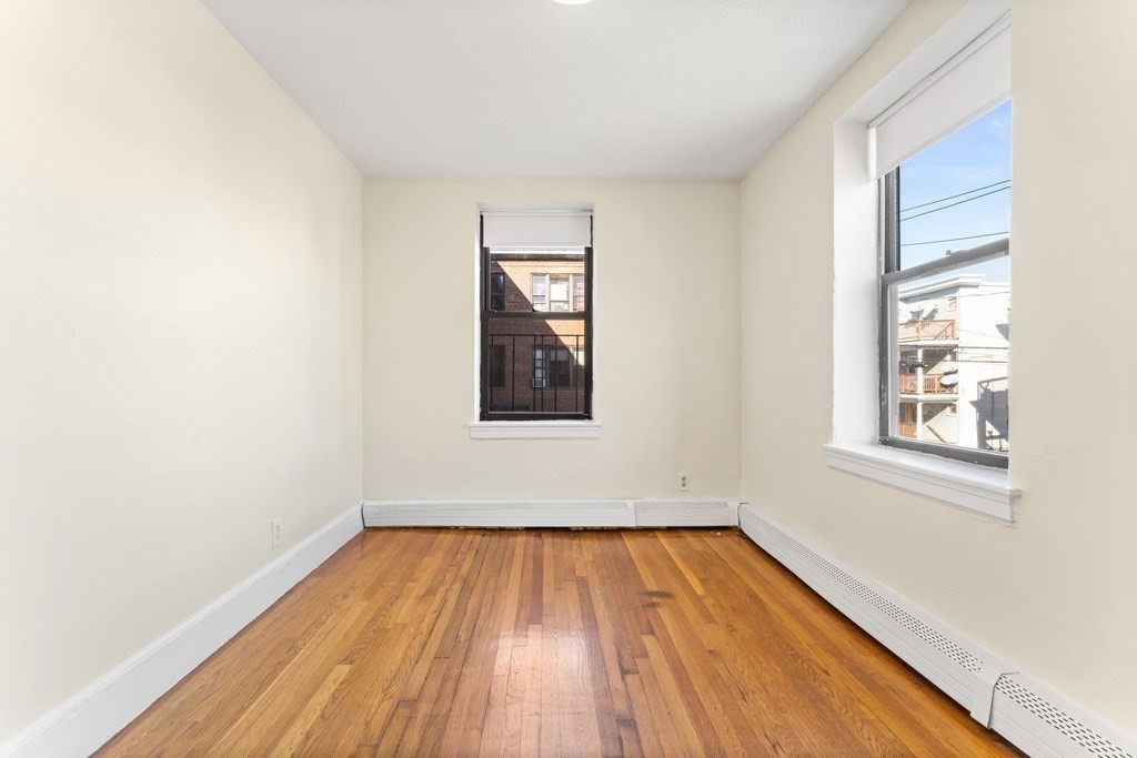 11 Victory Road, Unit 32 Boston, MA 02122 - Photo 7 of 16 an empty room with wooden floor and windows