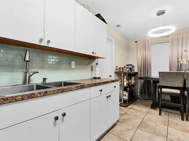 a kitchen with granite countertop a sink a stove and cabinets