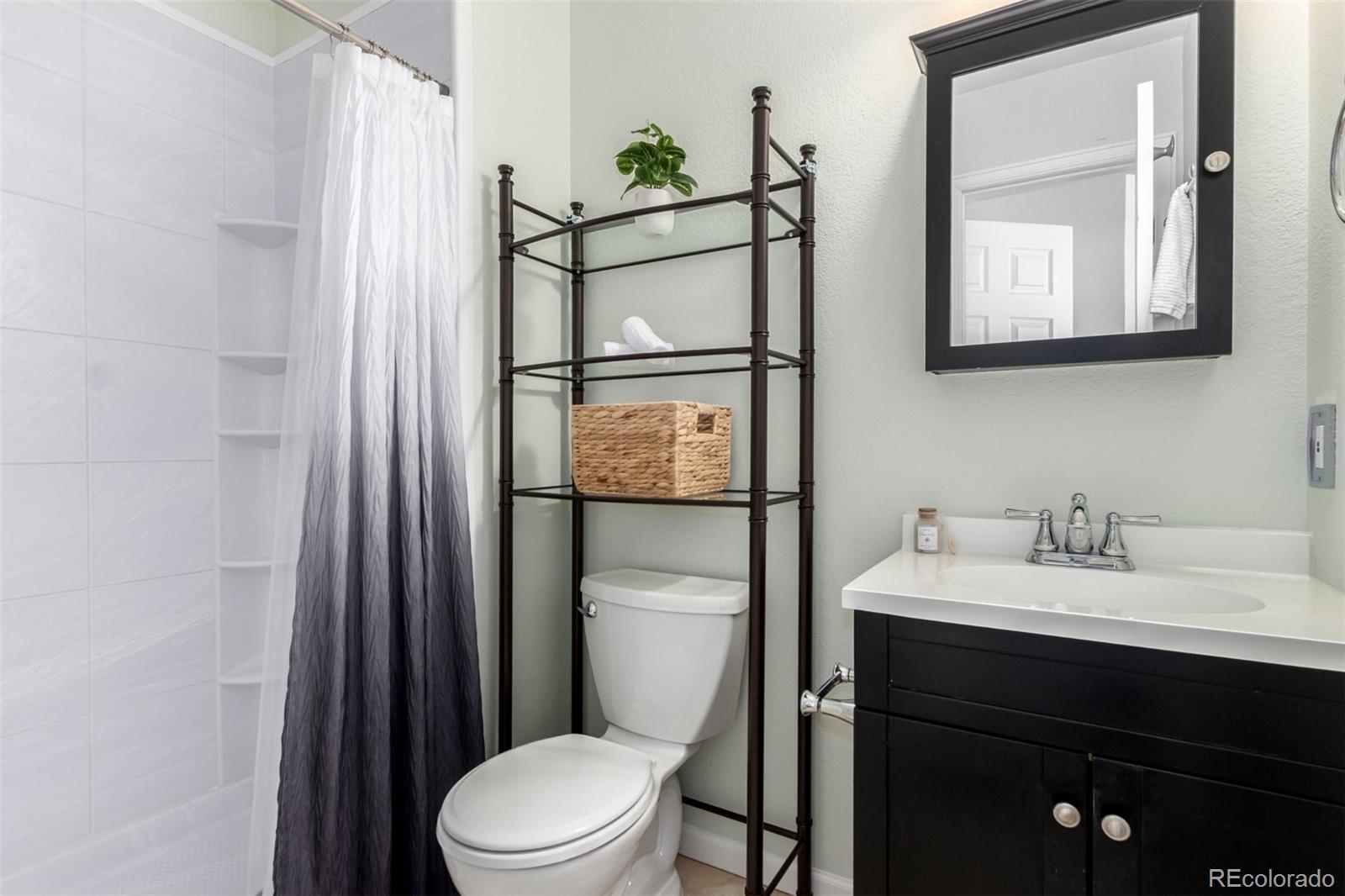 1885 South Quebec Way, Unit B22 Denver, CO 80231 - Photo 26 of 47 a bathroom with a toilet a sink and mirror