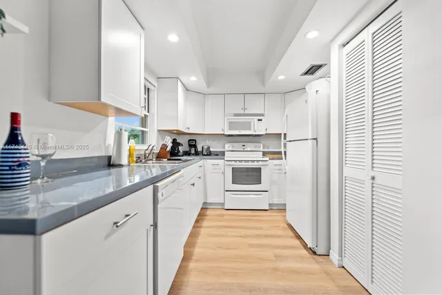 a kitchen with granite countertop white cabinets and white appliances