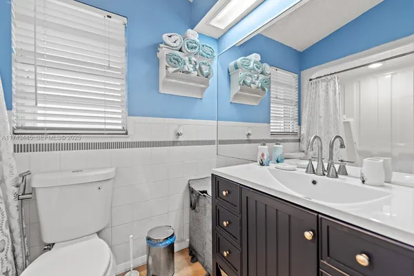 a bathroom with a sink a toilet a mirror and a window