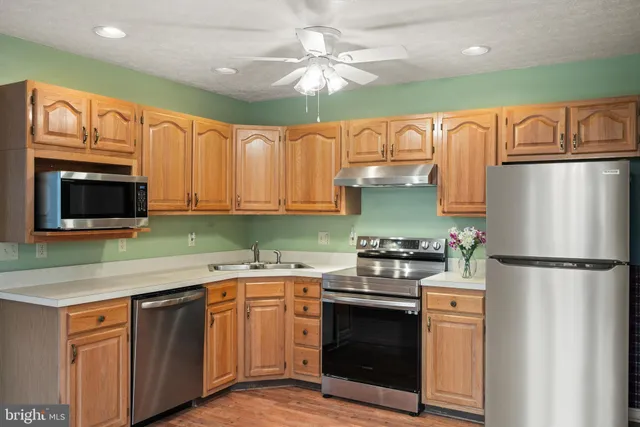 a kitchen with stainless steel appliances granite countertop a refrigerator a stove a sink dishwasher and a microwave oven with cabinets