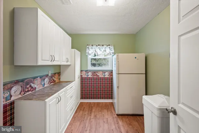 a kitchen with a refrigerator a stove and wooden floor