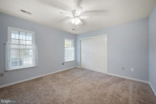 an empty room with windows and chandelier fan