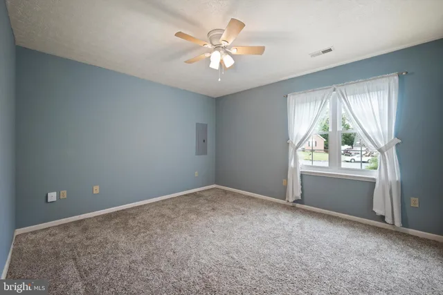 an empty room with windows and ceiling fan