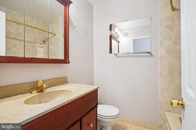 a bathroom with a granite countertop sink toilet and mirror