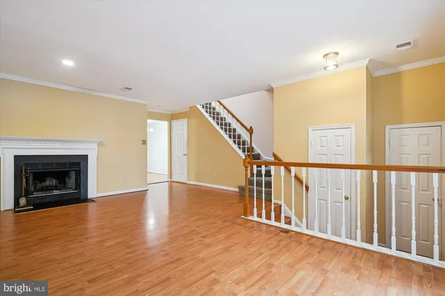 a view of an empty room with wooden floor fireplace and a window