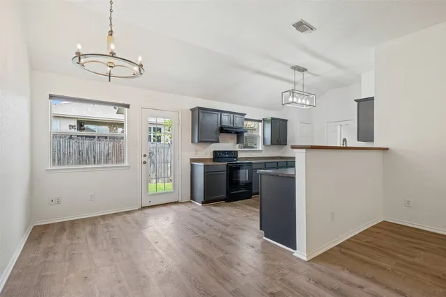 a kitchen with stainless steel appliances granite countertop a refrigerator a stove top oven a sink dishwasher and white cabinets with wooden floor