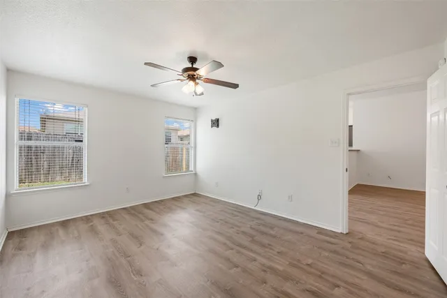a view of empty room with wooden floor and fan
