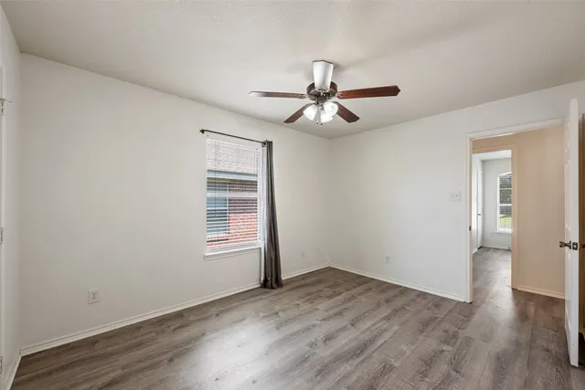a view of empty room with wooden floor and fan