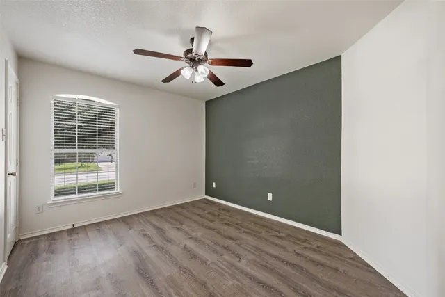 an empty room with windows and fan