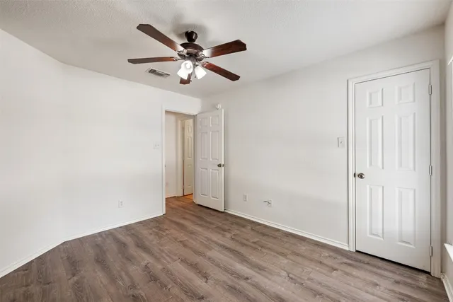 an empty room with wooden floor closet and fan