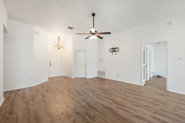 a view of a room with wooden floor ceiling fan and window