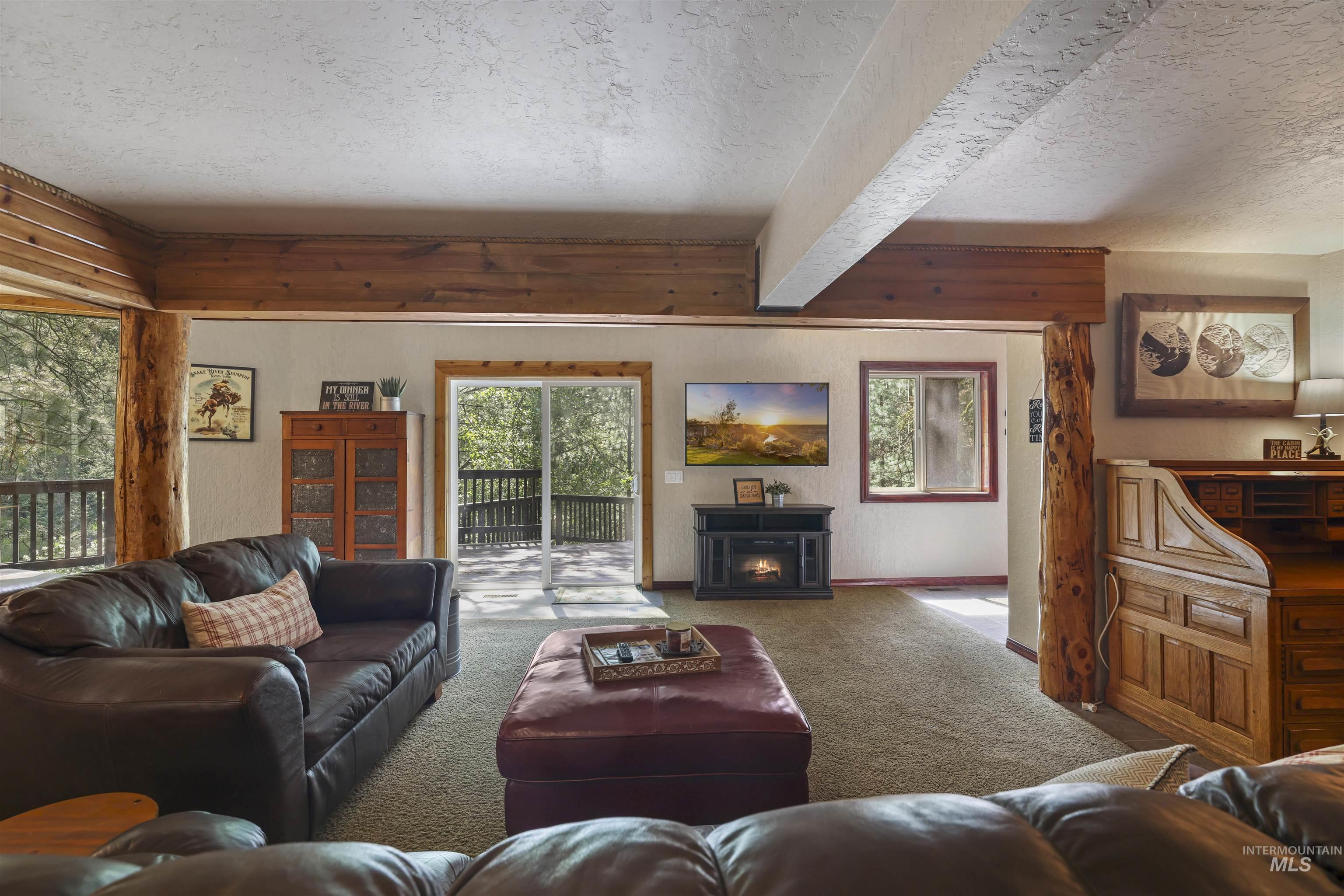224 Dakota Road Mountain Home, ID 83647 - Photo 2 of 50 Living area featuring wood-finish ceiling beams and support columns, a built-in fireplace, and carpet flooring