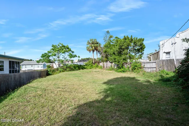 a view of a yard with plants and a large tree