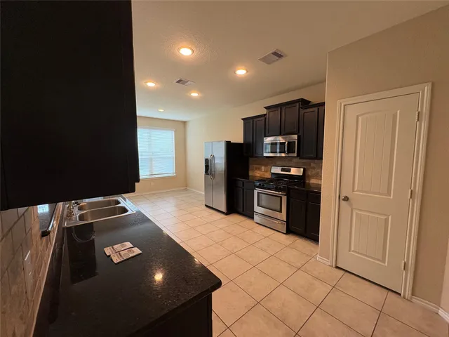 a kitchen with stainless steel appliances granite countertop a refrigerator and a stove top oven