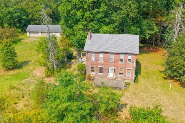 an aerial view of a house with swimming pool and large trees
