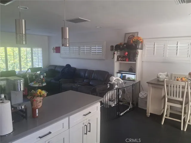 a kitchen with stainless steel appliances granite countertop a refrigerator a stove a kitchen island a dining table and chairs with wooden floor