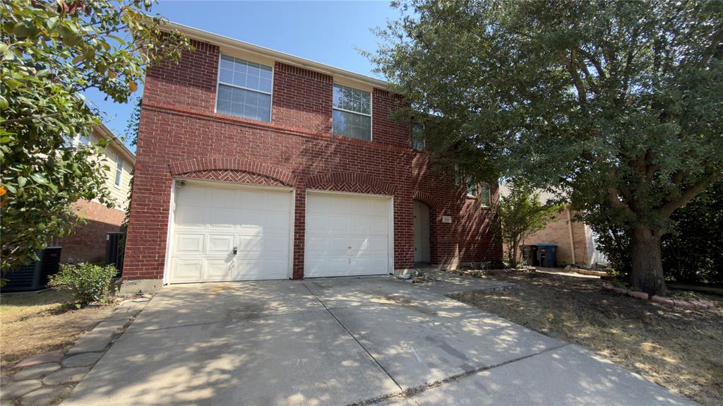 3401 Cheyenne Ranch Road Fort Worth, TX 76262 - Photo 2 of 17 Brick exterior with arched garage door detailing, dual white garage doors, and upper-level windows