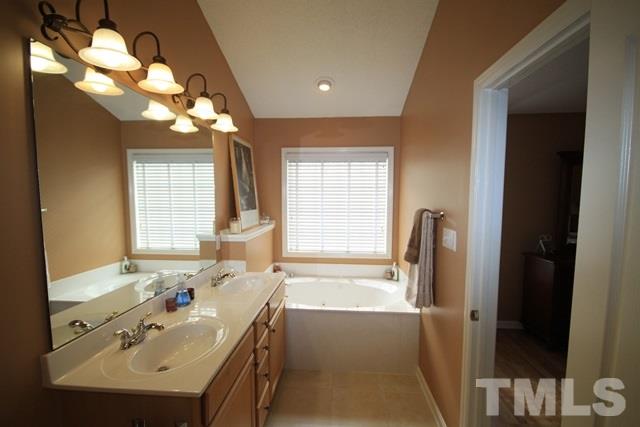 1439 Basinger Court Raleigh, NC 27612 - Photo 19 of 25 a bathroom with a sink a large mirror and a bathtub