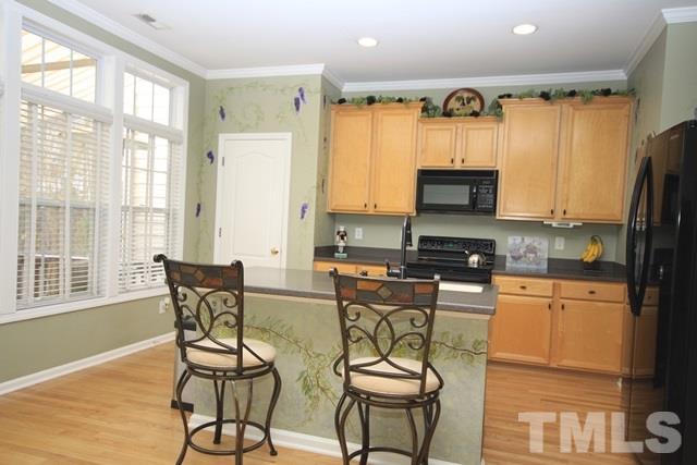 1439 Basinger Court Raleigh, NC 27612 - Photo 8 of 25 a kitchen with stainless steel appliances wooden floors and wooden cabinets
