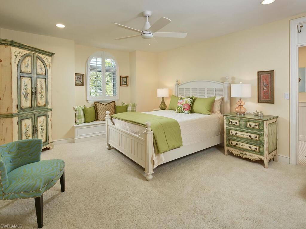 2750 Treasure Lane Naples, FL 34102 - Photo 18 of 28 a spacious bedroom with a bed a couch and a chandelier