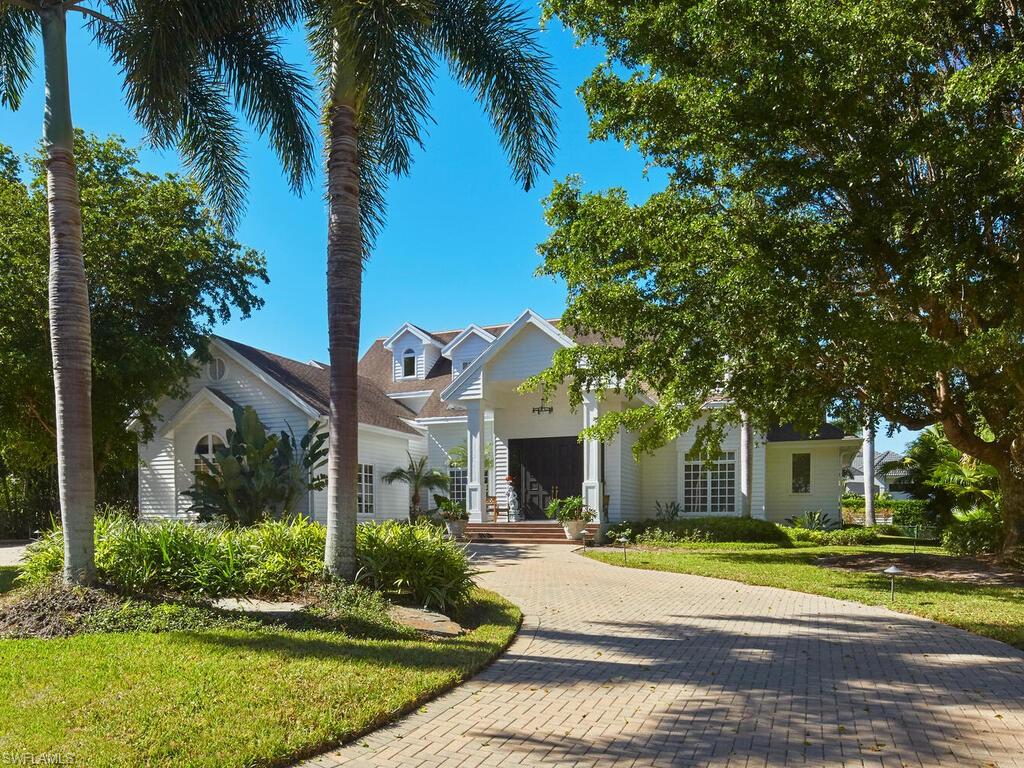 2750 Treasure Lane Naples, FL 34102 - Photo 28 of 28 a view of a white house with a large windows and a yard with palm trees