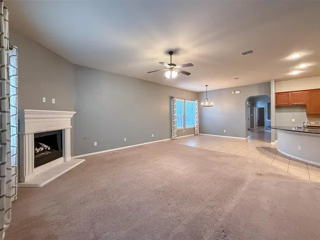 an empty room with fireplace and ceiling fan