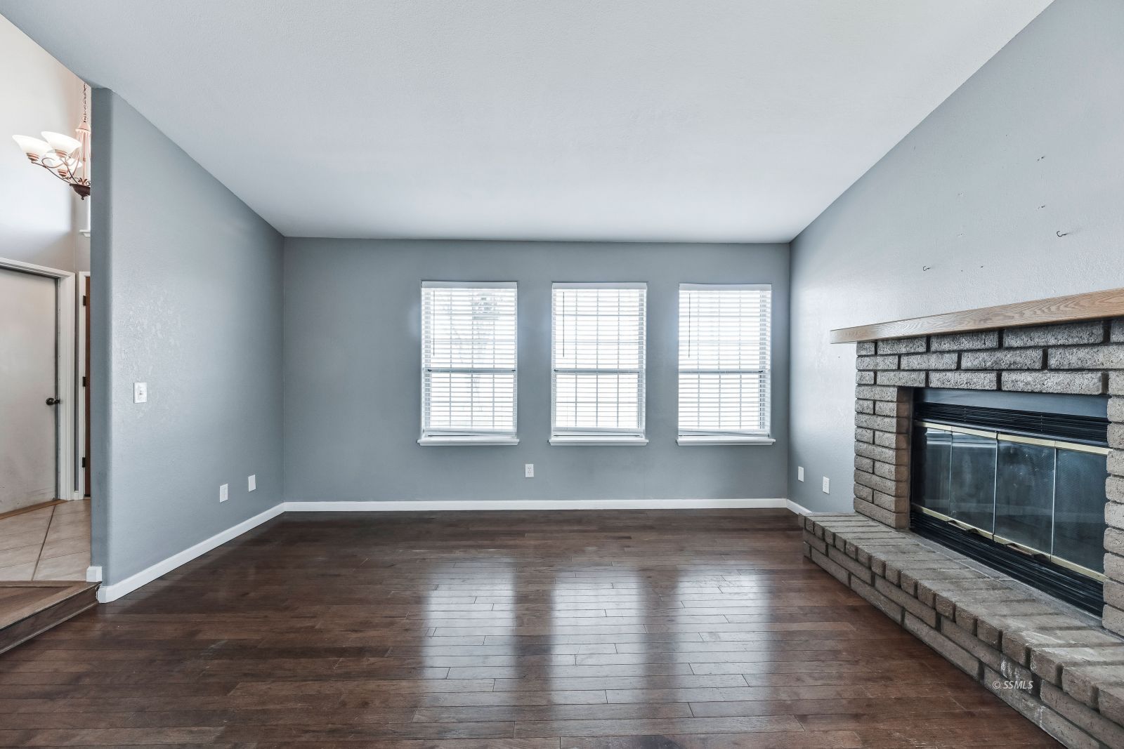 633 East Church Avenue Ridgecrest, CA 93555 - Photo 5 of 27 an empty room with wooden floor fireplace and windows