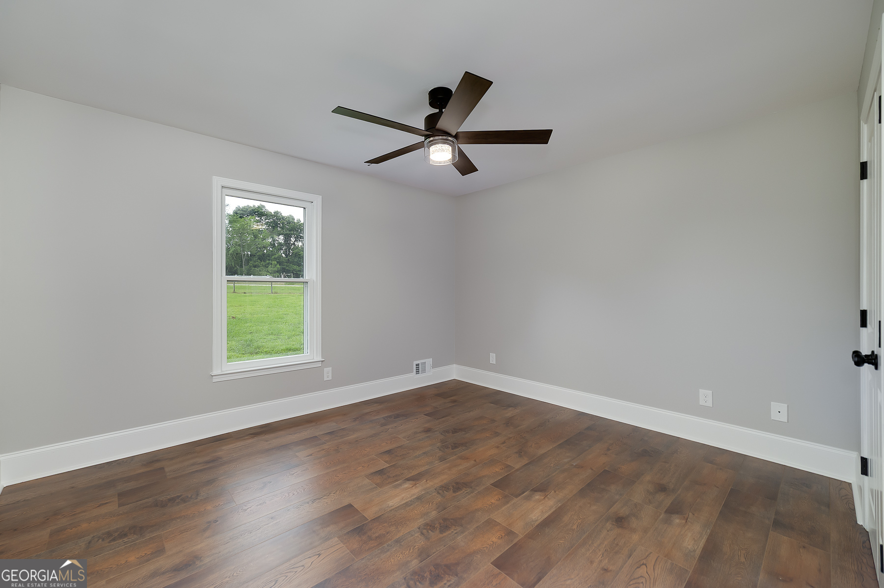 858 Pates Creek Road Stockbridge, GA 30281 - Photo 17 of 27 an empty room with wooden floor ceiling fan and windows
