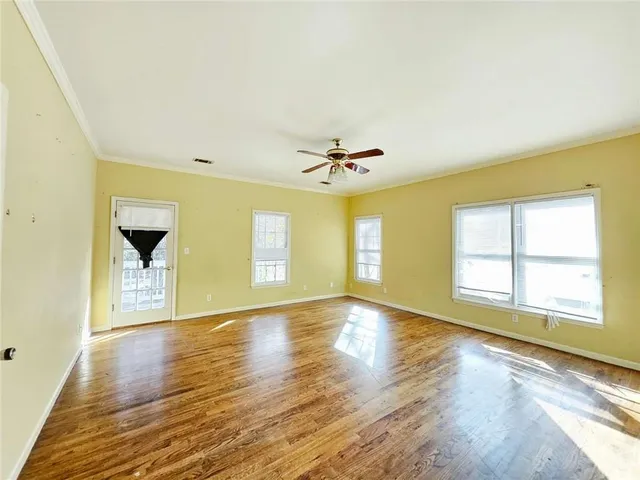 a view of an empty room with window and wooden floor